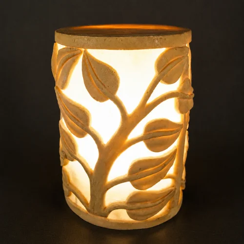 Sandstone garden light with vine-carved design glowing on a patio