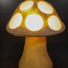 Glowing sandstone mushroom garden light with round carved cut-outs at night