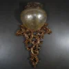 Antique Carved Wall Light with glowing amber shade and silver-brown finish