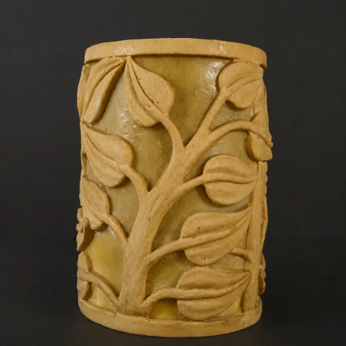 Sandstone garden light with vine-carved design glowing on a patio