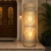 Faux sandstone double lantern pedestal with warm glowing light and intricate decorative pattern