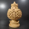Sandstone garden light ball glowing warm light through carved floral pattern outdoors