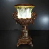 Ornate fiber glass pedestal lamp with glowing shade and floral details