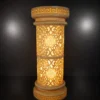 Faux sandstone double lantern pedestal with warm glowing light and intricate decorative pattern
