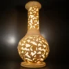 Sandstone flared vase garden light with intricate vine and floral carving and warm glowing illumination